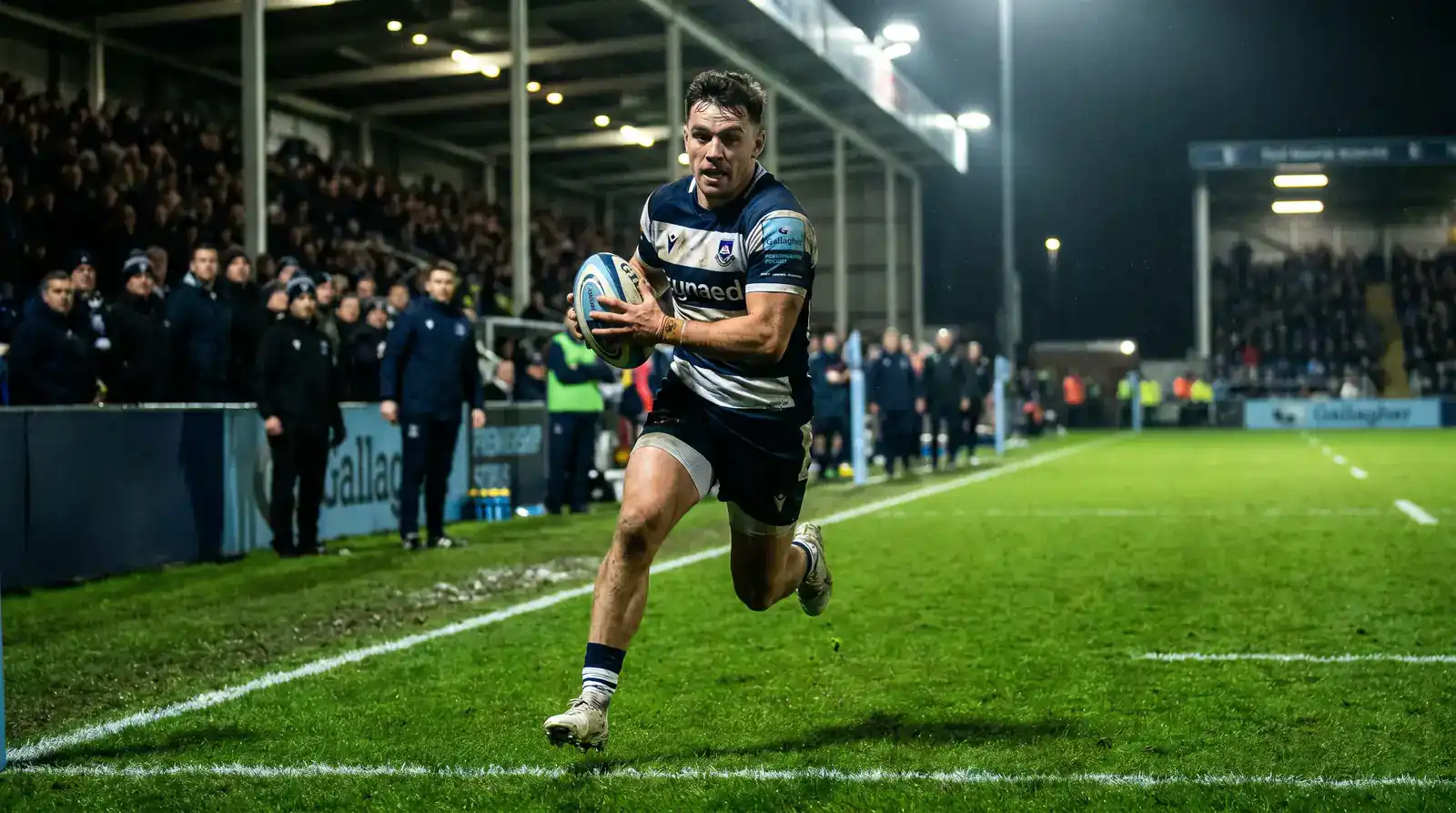 Rugby winger crossing the try line during a Premiership match under floodlights